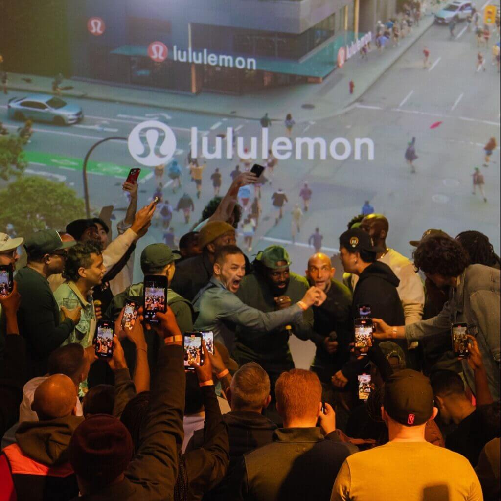 That Good Co A group of people excitedly pose for photos in front of a Lululemon display projected on a wall, embodying the vibrant energy reminiscent of That Good Co's community spirit.