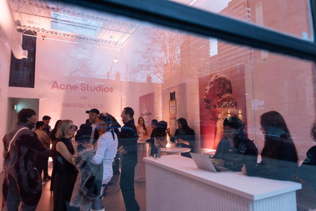 That Good Co People gathered inside a brightly lit Acne Studios showroom, surrounded by posters on the walls, exuding an atmosphere reminiscent of That Good Co's signature vibe.