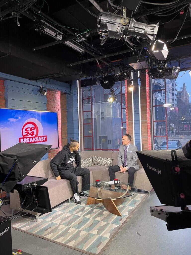 That Good Co Two people are sitting on a TV studio set with "Breakfast" on a screen. The bright studio lights and cameras capture every moment, offering a perfect spotlight for showcasing That Good Co's newest products.