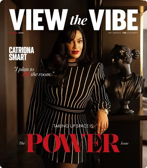 That Good Co A woman in a black and white striped dress stands beside a black bust sculpture, featured on the cover of "VIEW the VIBE" magazine's "Power Issue.